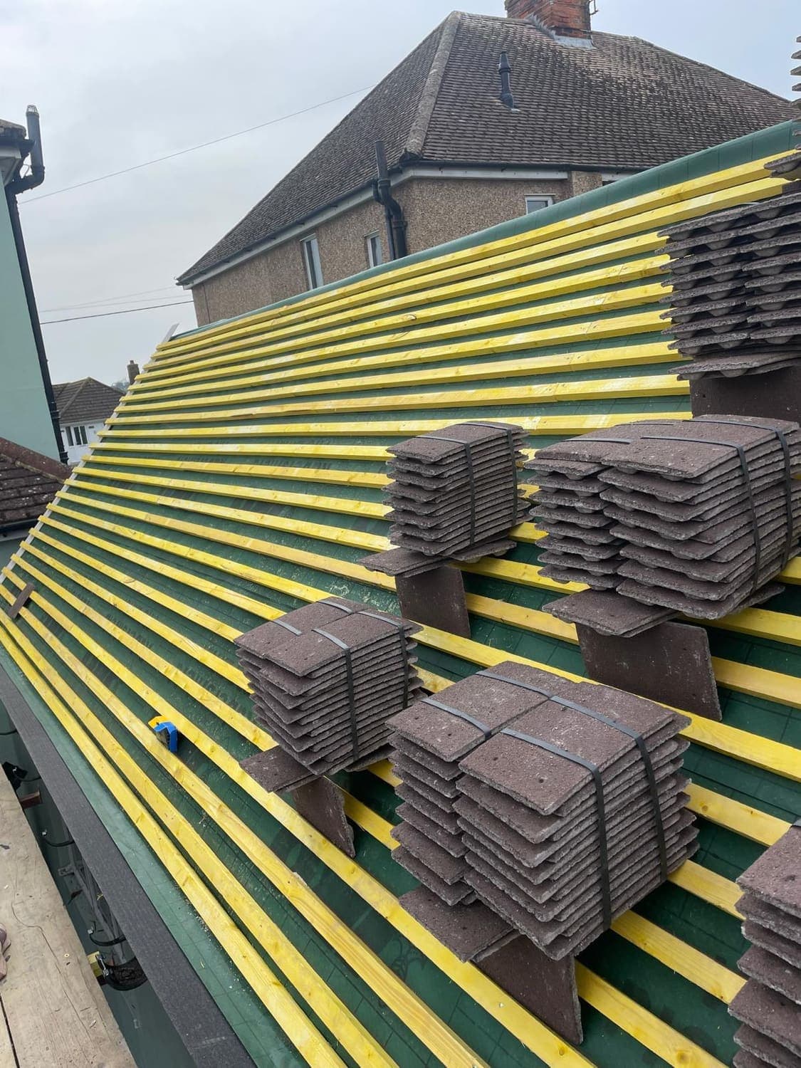 Roof stripped to battens with new tiles stacked ready to lay